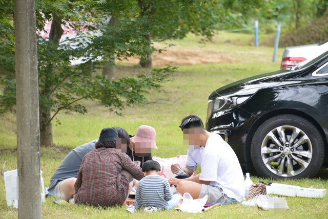 지난 10일 오전 청주 매화공원 주차장에서 한 일가족이 고기를 구워 먹고 있는 모습. 뒤에 막걸리 병도 있어 음주운전 위험성도 있다.(사진=신우식 기자)