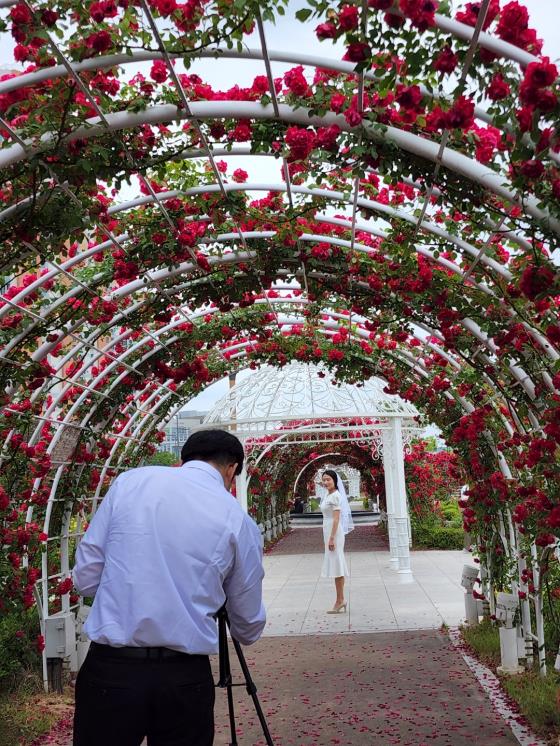 예비신랑이 예비신부를 촬영존에 세우고 카메라 각도를 맞추고 있다.