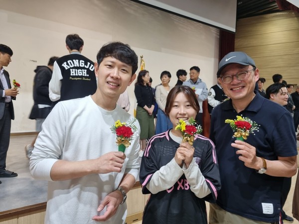 꽃을 받은 교직원들이 활짝 웃으며 기뻐하고 있다.