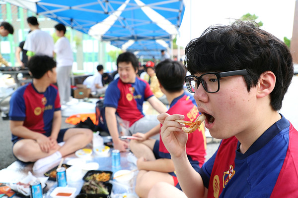 삼겹살 파티 행사에서 한 학생이 구운 고기를 맛있게 먹고있다.