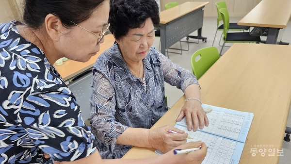 ▲신갑식(왼쪽) 강사가 서도화씨의 한글공부를 도와주고 있다.