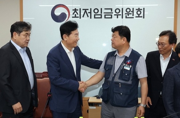 최저임금위원회 사용자위원 운영위원인 류기정 한국경영자총협회 전무(왼쪽 두 번째)와 근로자위원 운영위원인 류기섭 한국노총 사무총장(오른쪽 두 번째)이 10일 정부세종청사에서 열린 제12차 전원회의에서 내년 최저임금을 시간당 1만320원으로 17년만에 합의로 결정한 뒤 악수하고 있다.