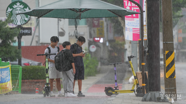 24일 청주시 청원구 율량동에서 시민들이 갑작스럽게 내린 폭우를 피해 그늘막 아래서 신호를 기다리고 있다.  [사진=손상훈 기자]