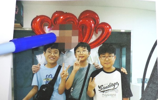 아이들 뒤에 있는 최 시장이 모자이크(파란색 사인펜으로 가리킨 부분) 처리된 확대 장면.